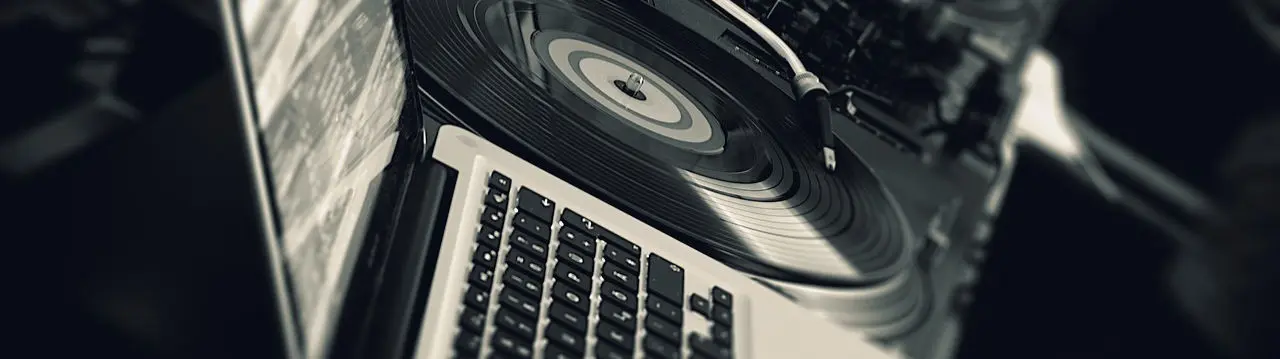 Un ordenador portátil junto a unos platos de Dj